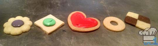 Various cookies in unique shapes, being a flower, a square, a heart, a donut, and a checkerboard.