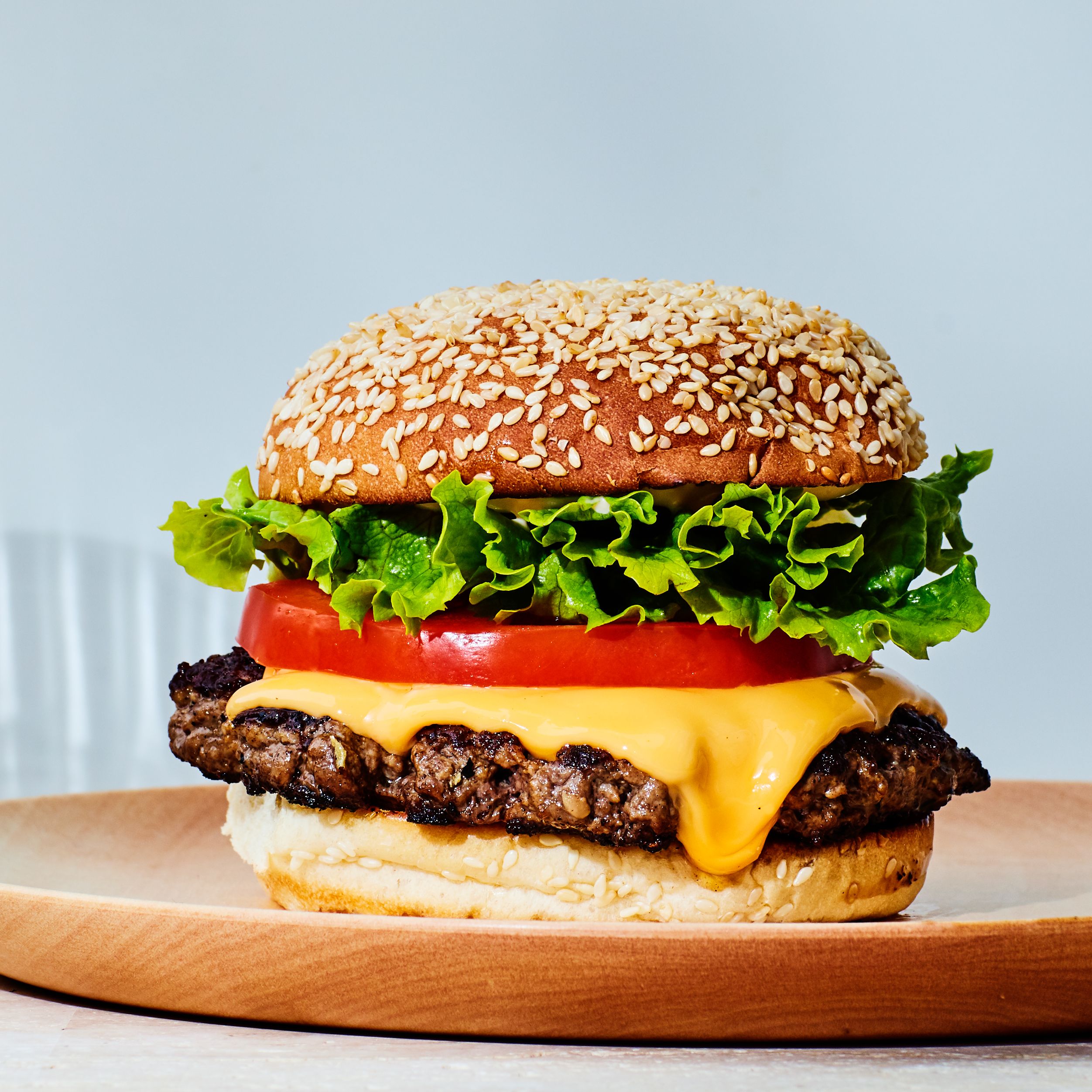A cheeseburger with a sesame bun and topped with lettuce and tomato.